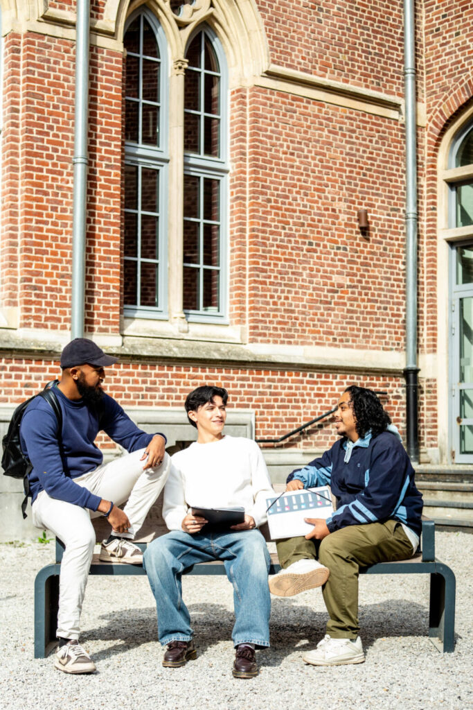 Moment d'échange et de discussion entre trois étudiants sur le campus universitaire.